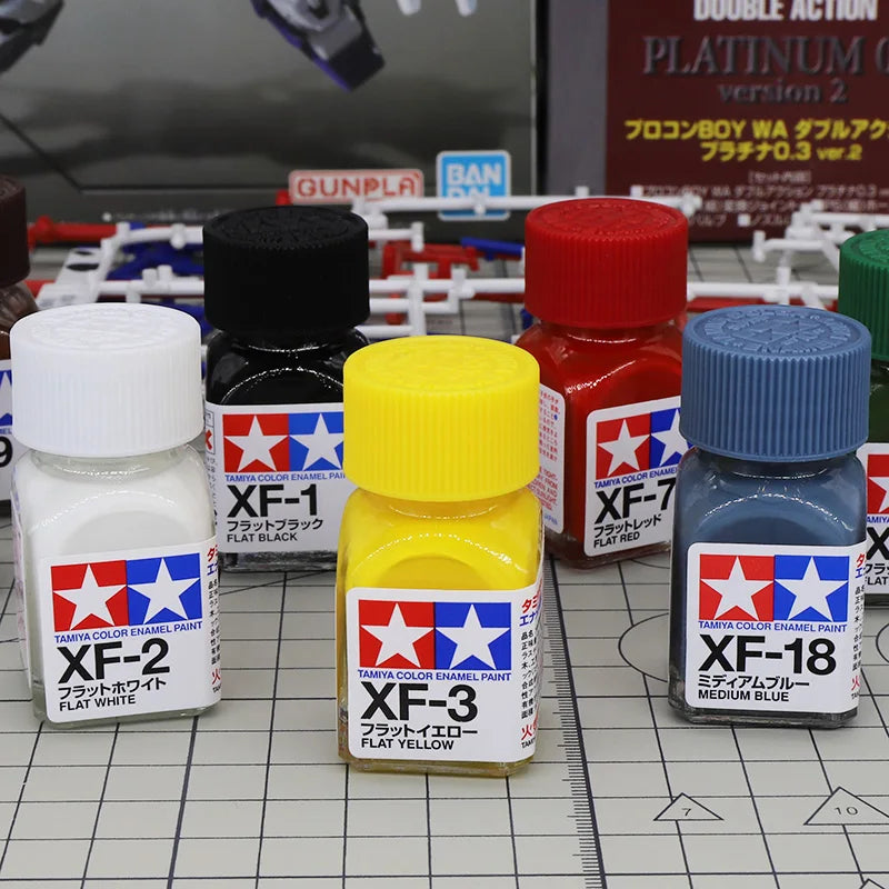 A set of Tamiya Color Enamel Paints including XF-1, XF-2, and XF-3 bottles with red caps.