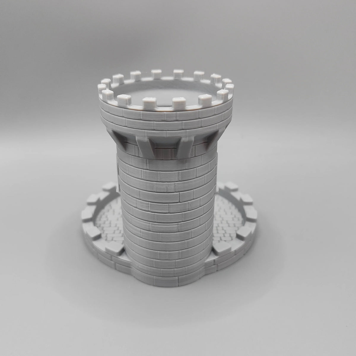 A gray medieval castle dice tower with a tray for tabletop games.