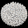A pile of small white acrylic alphabet letter beads for jewelry making