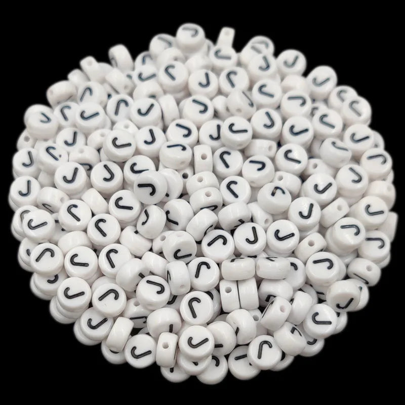 A pile of small white acrylic alphabet letter beads for jewelry making