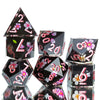 A set of black and pink resin polyhedral dice with floral designs shown from an angle.