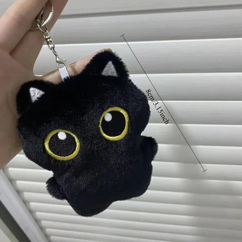 A black plush cat with large yellow eyes is shown against a white slatted background.