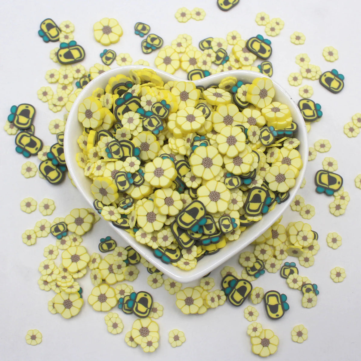 Assorted polymer clay sunflower and bee slices scattered on a white background.