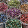 A collection of various colored glass beads in small clear containers for DIY jewelry making