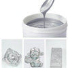 A silver glitter paint is shown being dispensed from a spatula into a white container, with finished silver decorative items 