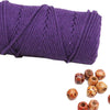 Purple natural cotton macrame rope coiled on a white background with decorative knots scattered below.