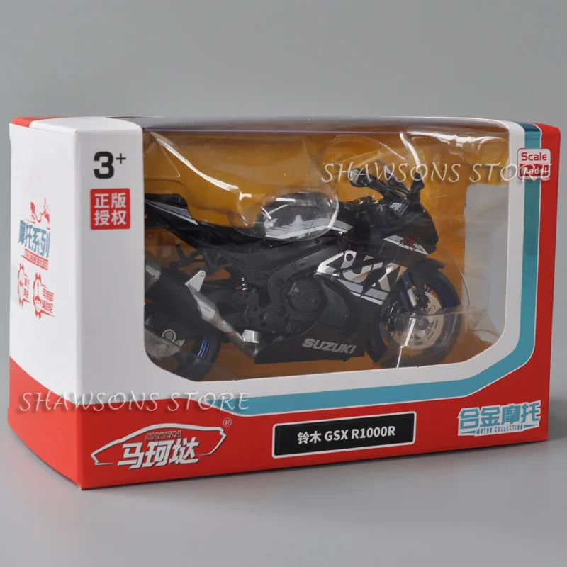 A diecast model of a black Suzuki GSX-R1000R motorcycle is displayed in its packaging box.