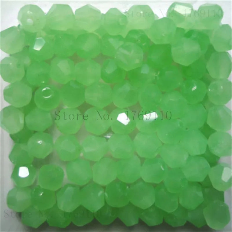 Une pile de perles de cristal vert clair et facettées pour la fabrication de bijoux DIY.