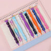 A collection of precision diamond painting pens in various colors arranged on a lined notebook page.