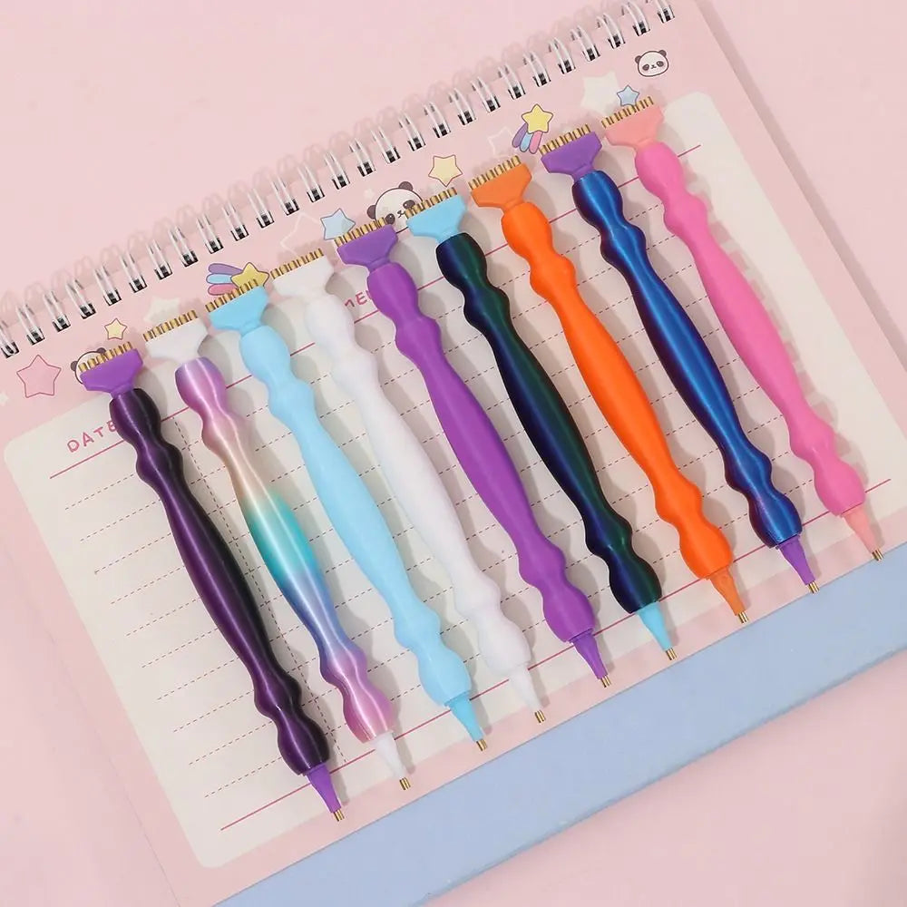 A collection of precision diamond painting pens in various colors arranged on a lined notebook page.
