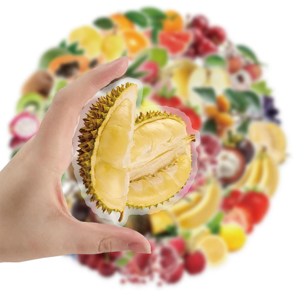 A hand holds a transparent sticker featuring sliced yellow fruit on a background of various colorful berries and fruits.