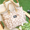 A beige floral canvas tote bag with multiple pockets resting on a wooden surface.