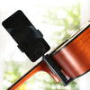A black phone is mounted on a clamp holder attached to the neck of a wooden guitar.