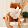 An adorable sitting kitten plush doll with orange and white fur being held by a person.