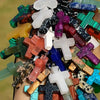 A collection of natural stone cross pendants in various colors and shapes held in a hand.