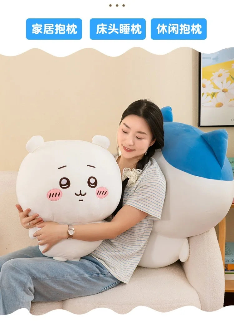 A woman is sitting on a sofa holding a white Chiikawa plush doll, with other related plush toys displayed in the background.