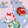 A set of soft rubber pull-back toy cars, including a red car and two green/pink animal-themed cars, on a light blue track.