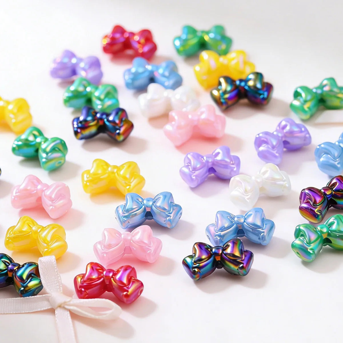 A collection of colorful acrylic bow beads in various shades including pink, purple, yellow, and green scattered on a white s