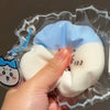 A hand is holding a squishy stress relief toy shaped like a white and light blue face inside clear plastic packaging.