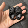 A pair of black fashion slippers designed for 1/6 BJD dolls, shown in a hand.