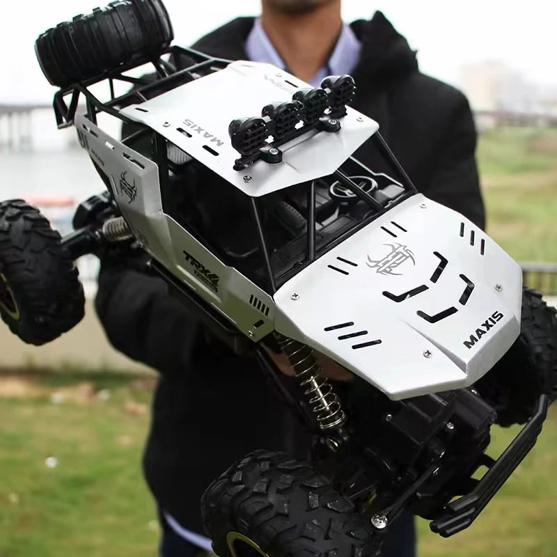 A black and white 4WD off-road monster truck with a white front panel and large tires is being held by a person outdoors.