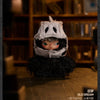 A small plush doll resembling a masked figure with dark hair and light eyes, displayed on a wooden surface.