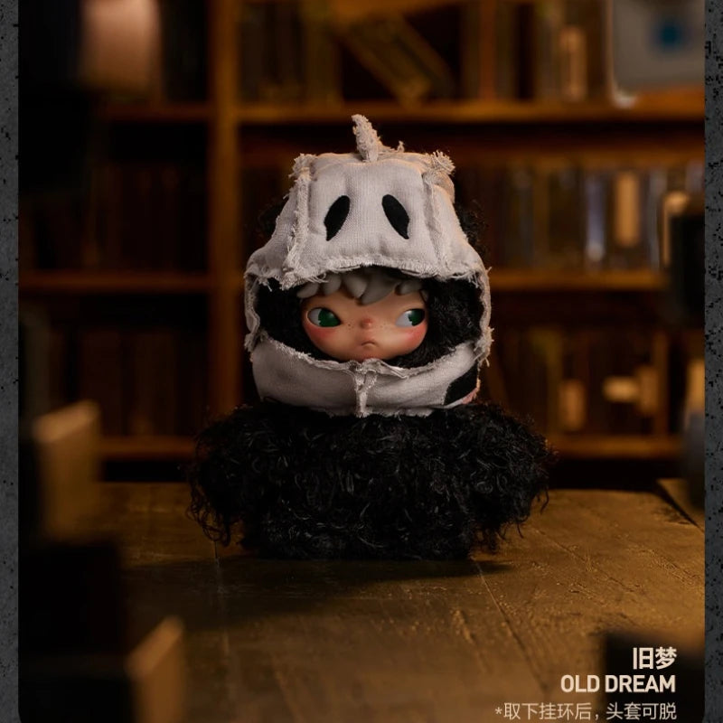 A small plush doll resembling a masked figure with dark hair and light eyes, displayed on a wooden surface.
