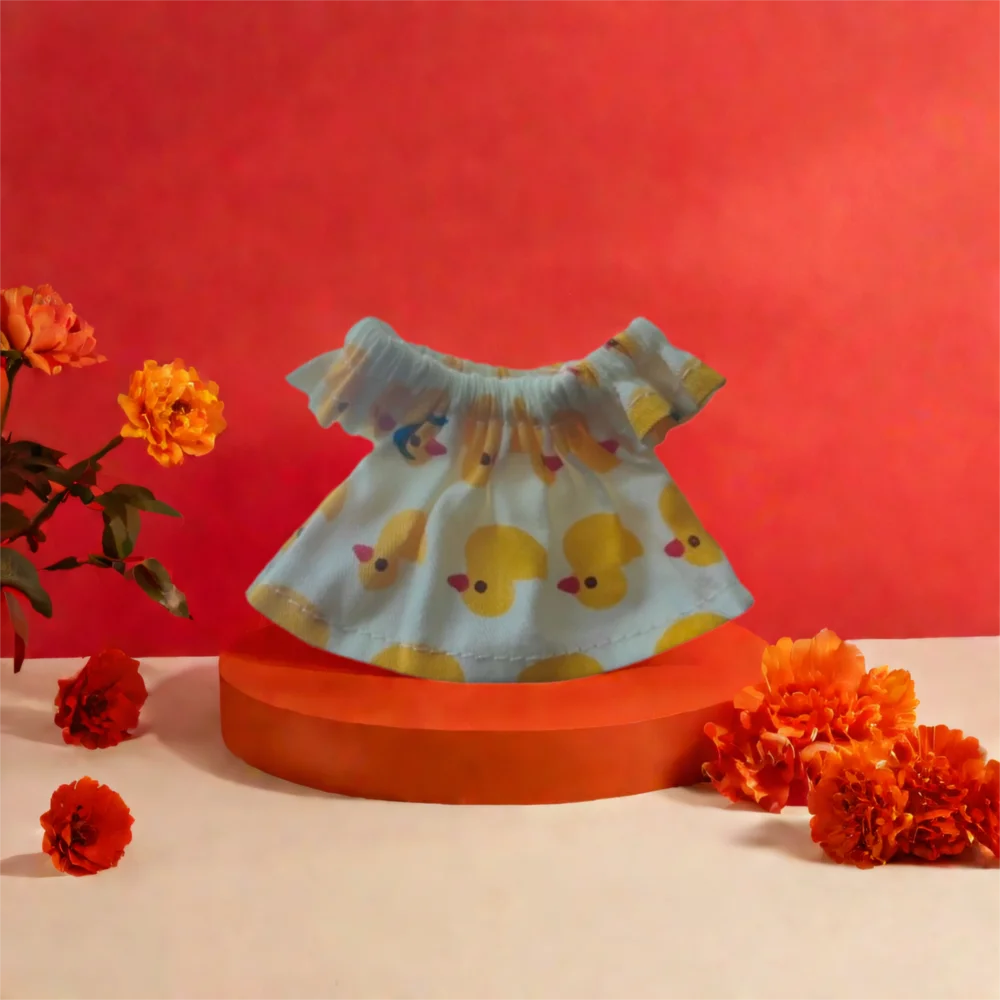 A light blue ruffled top with yellow duck print displayed against a red background.