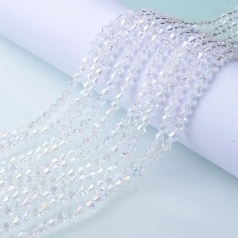 Clear faceted glass crystal beads in a strand draped over a white surface.