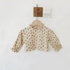 A light beige vintage floral baby girl outfit set featuring a blouse and romper, hanging on a wooden hanger.