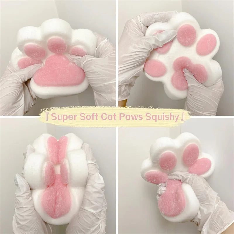 A pair of pink and white squishy cat paw toys are shown being held in gloved hands.