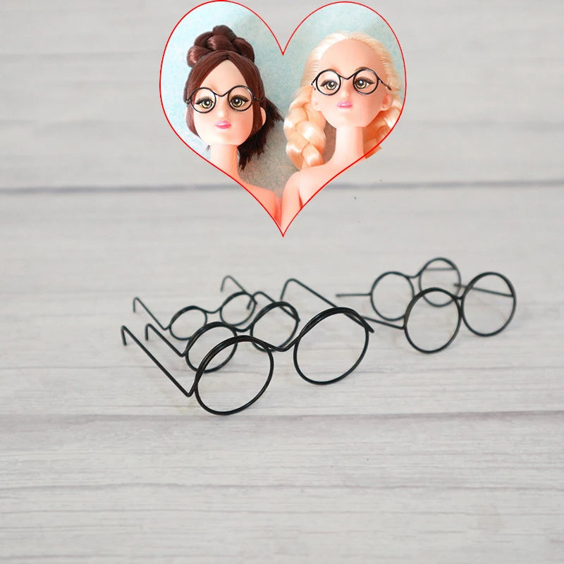 A heart-shaped frame features two dolls with round metal glasses frames.