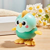 A cute, light teal wind-up chick toy with yellow feet and a pull chain, resting on a wooden surface.