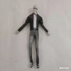 A full-body shot of a poseable plush doll dressed in a black shirt and gray pants, standing against a white wall.