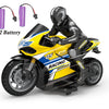 A black and yellow 1:10 scale remote control stunt motorcycle with a rider figure and two batteries.