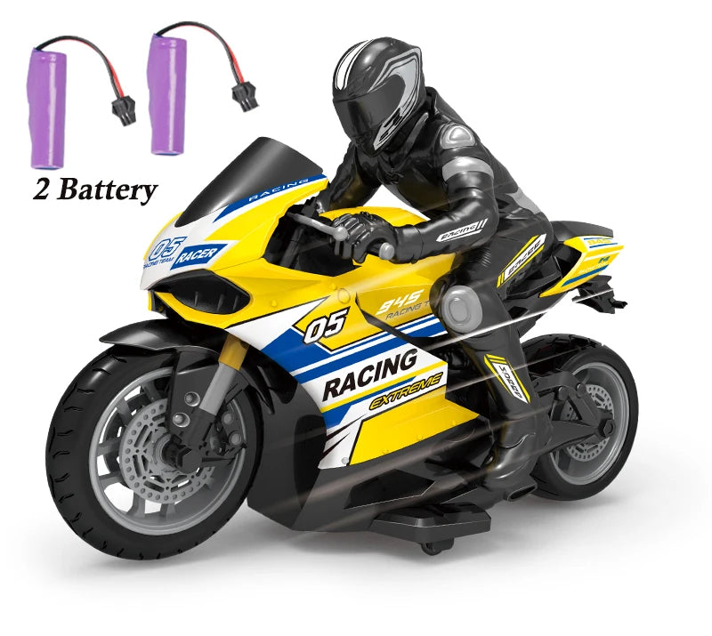 A black and yellow 1:10 scale remote control stunt motorcycle with a rider figure and two batteries.