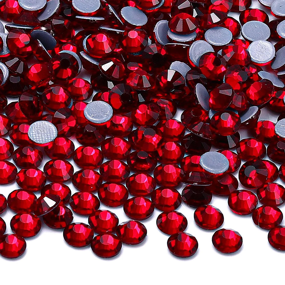 A close-up view of various red and silver glass crystal rhinestones scattered on a white background.
