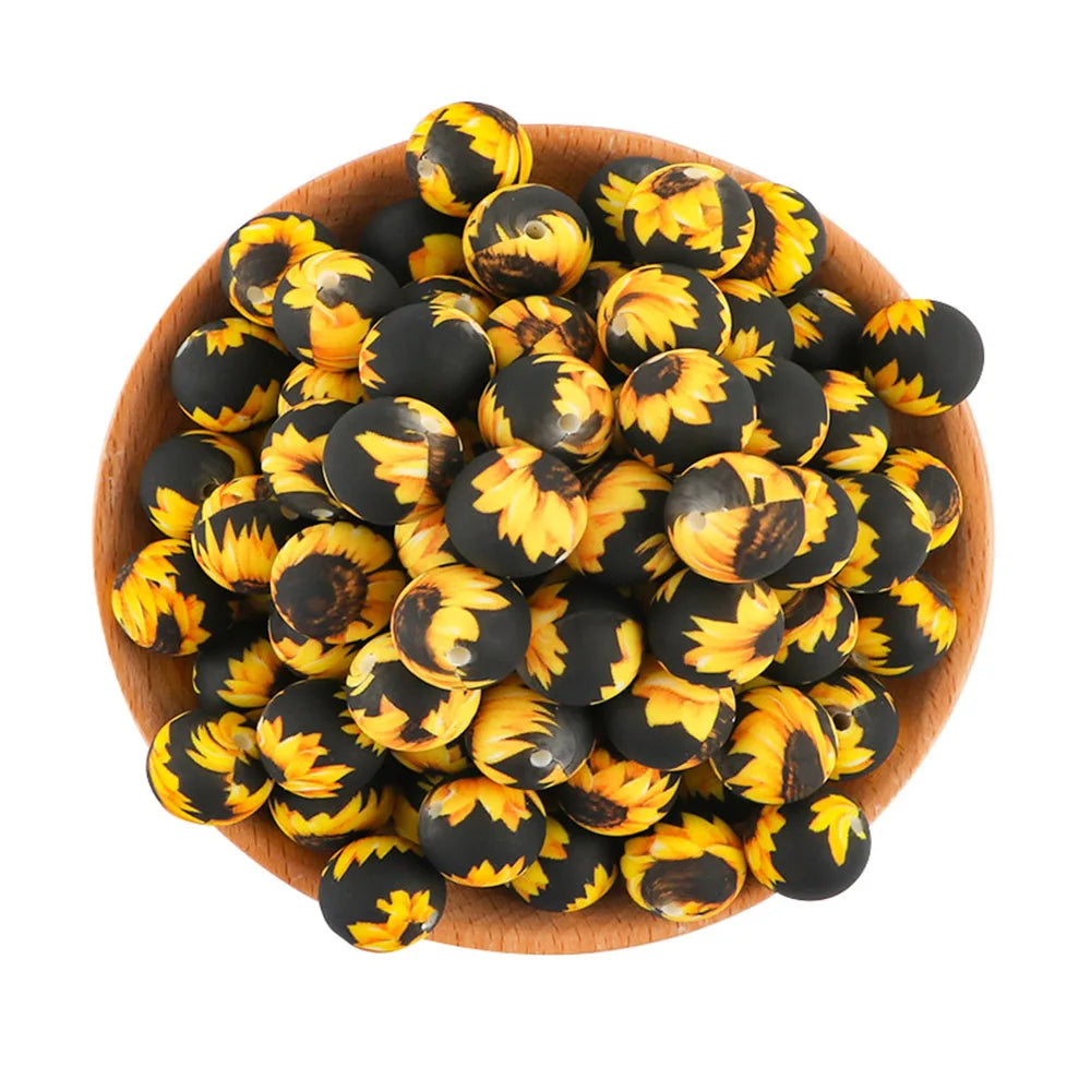 A pile of black and yellow silicone beads for jewelry making in a wooden bowl.