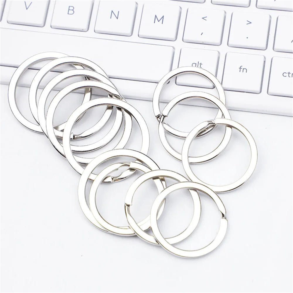 A collection of silver metal keychain hooks, swivel clasps, and key rings laid out on a white surface.