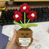 Handmade crochet plant with a brown pot and red flowers displayed on a white surface.