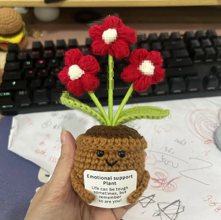 Handmade crochet plant with a brown pot and red flowers displayed on a white surface.