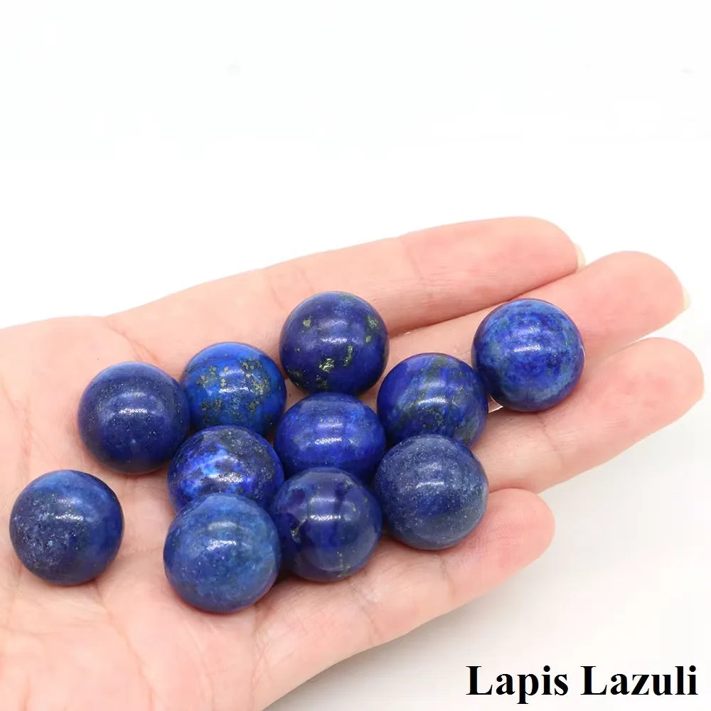 A hand holds several deep blue lapis lazuli crystal spheres.