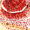 A pile of red and gold flatback resin rhinestones scattered on a light background.
