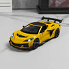 A yellow 1:32 scale diecast supercar model with a black spoiler and opening doors on a white marble surface.