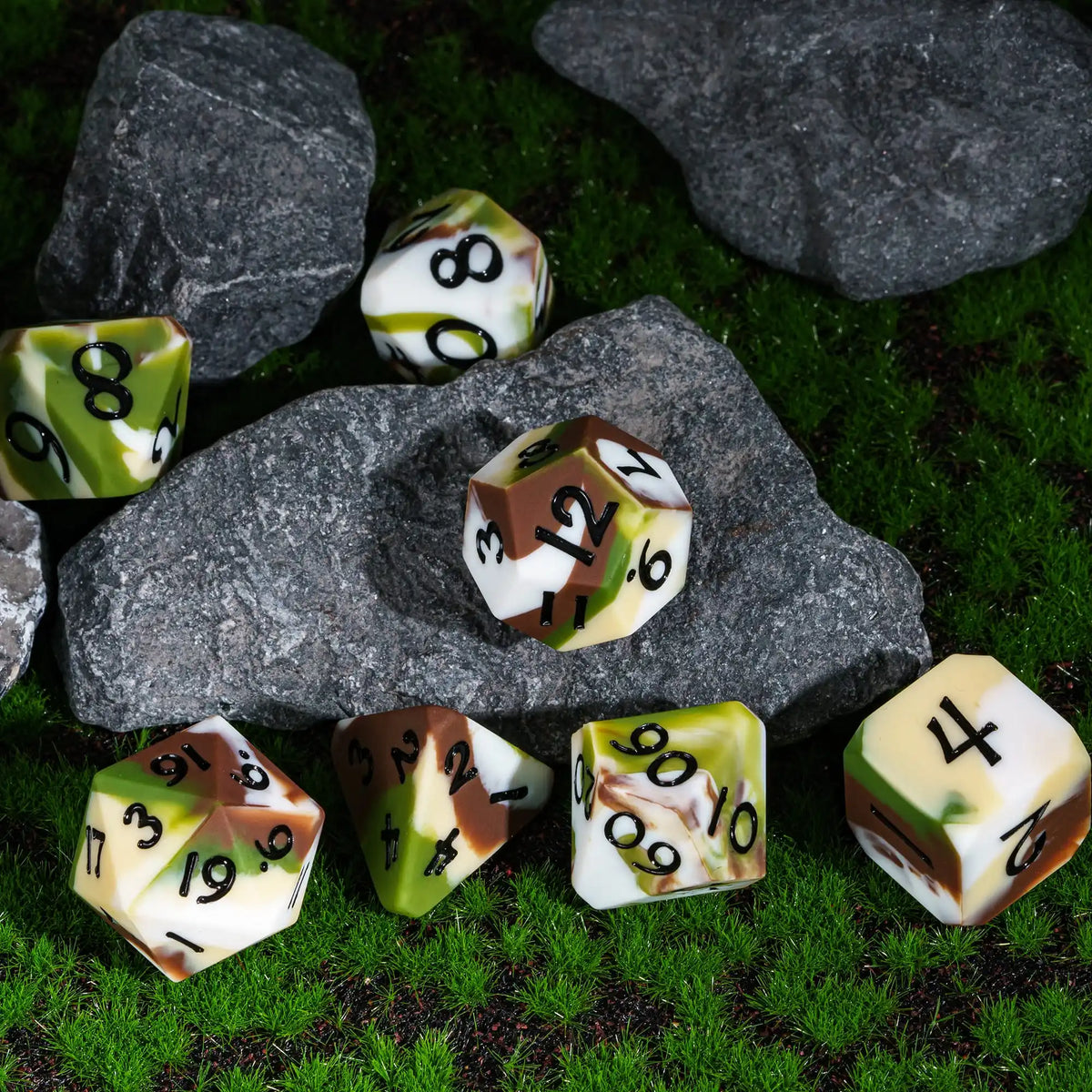 A set of silicone polyhedral dice resting on mossy rocks and green grass.