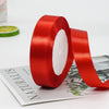 A roll of red satin ribbon for gift wrapping and decorations is shown next to a green lime slice.