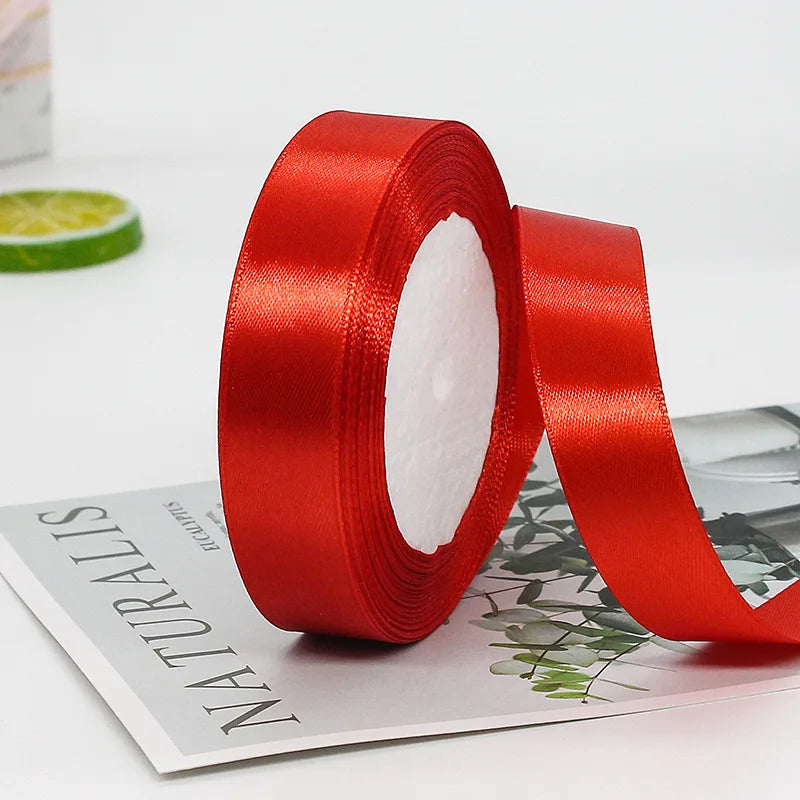 A roll of red satin ribbon for gift wrapping and decorations is shown next to a green lime slice.