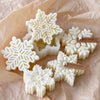 White snowflake silicone molds for candle, soap, and wax melts displayed on brown paper.