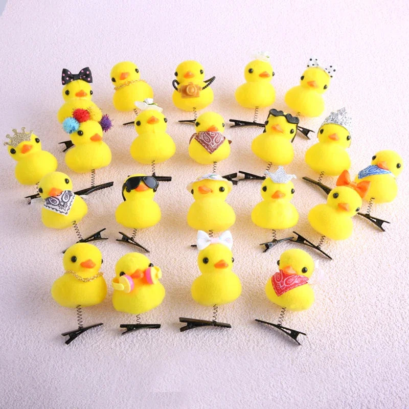 A collection of yellow 3D duck plush hair clips with various decorations arranged on a white background.
