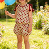 A young girl wearing a red and white polka dot summer two-piece set outdoors.